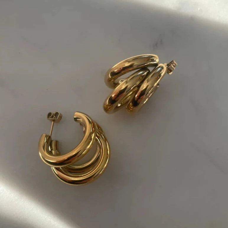 Detailed shot of Triple Hoop Gold Earrings shining brightly