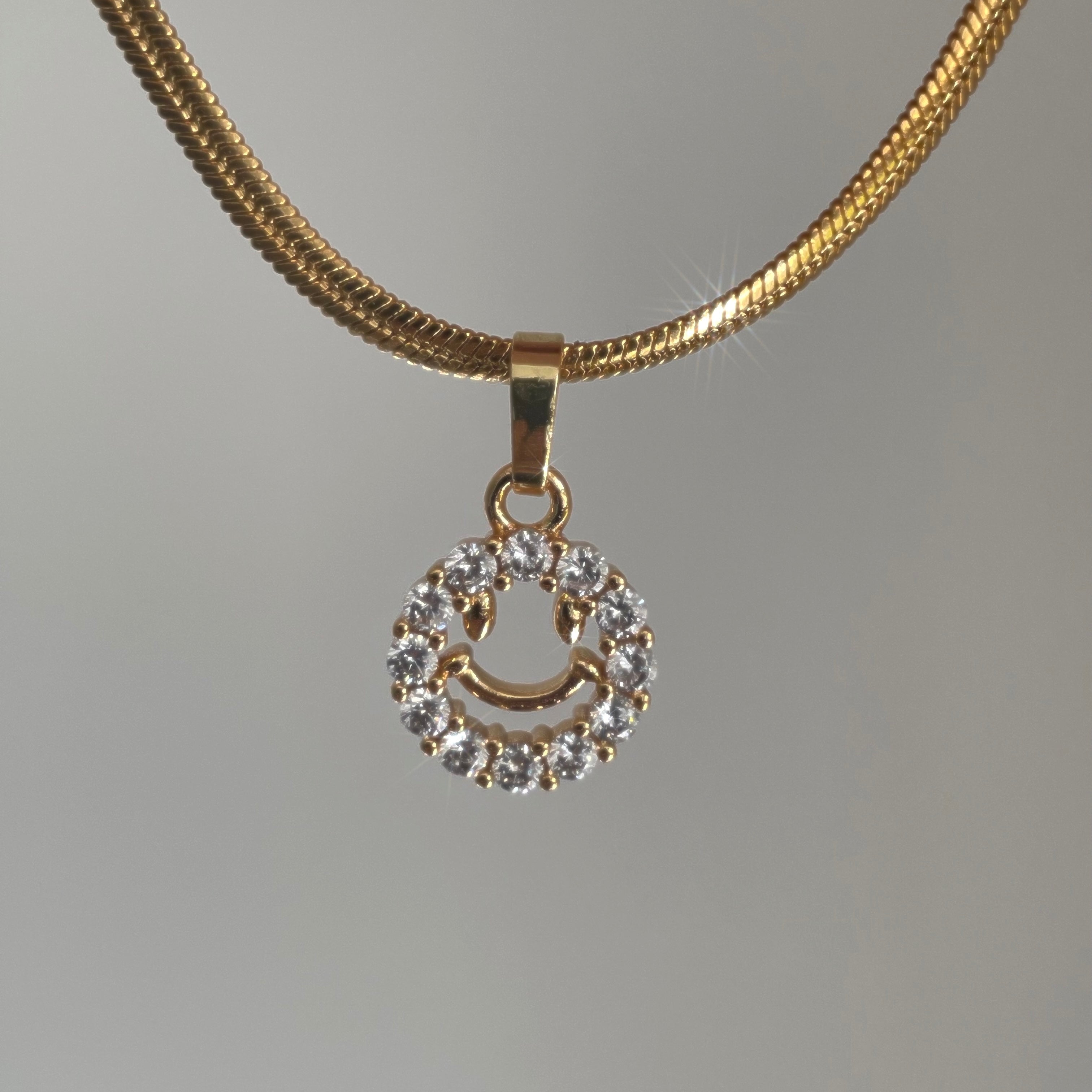Elegant gold necklace featuring a smiley face pendant.